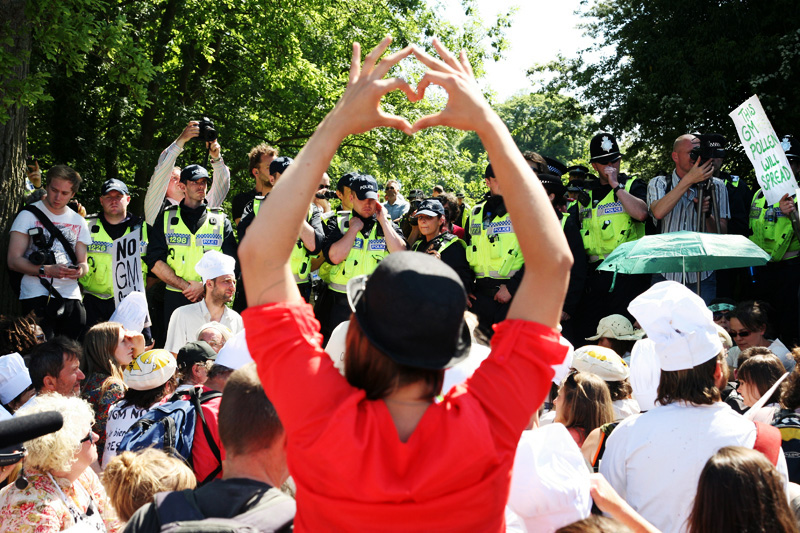 A protester makes a heart symbol in front of police forces outside the Rothamsted research centre in Hertfordshire, <br />where hundreds of activists gathered to demonstrate against open air trials of genetically modified wheat.<br />UNITED KINGDOM, Harpenden | 2012